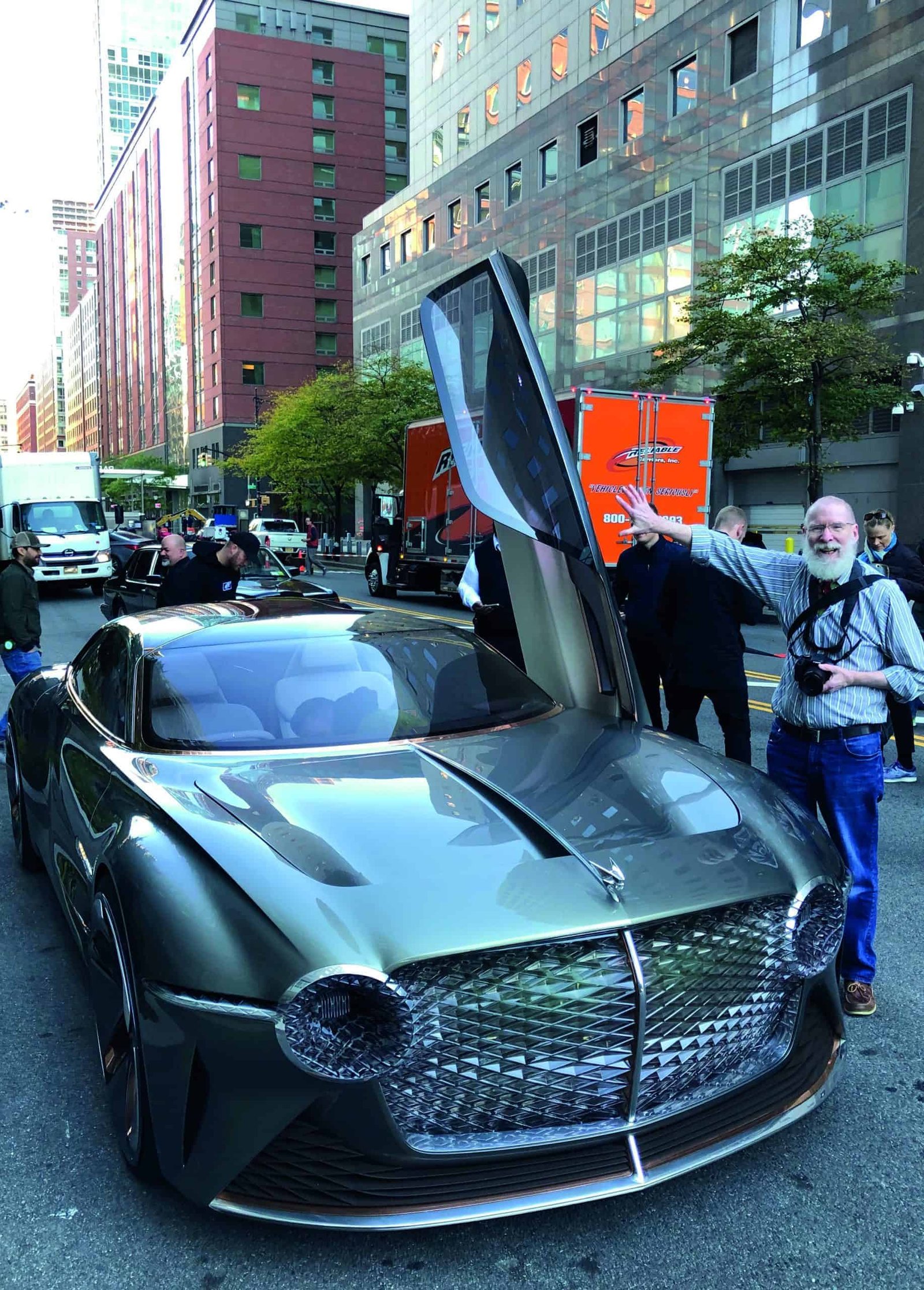 A man is standing next to a futuristic car invention.