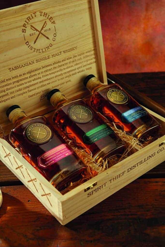 Three bottles of whiskey made from grain in a wooden box.