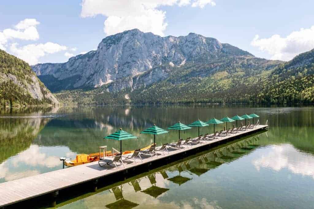 A beautiful dock with chairs and umbrellas on a serene lake.