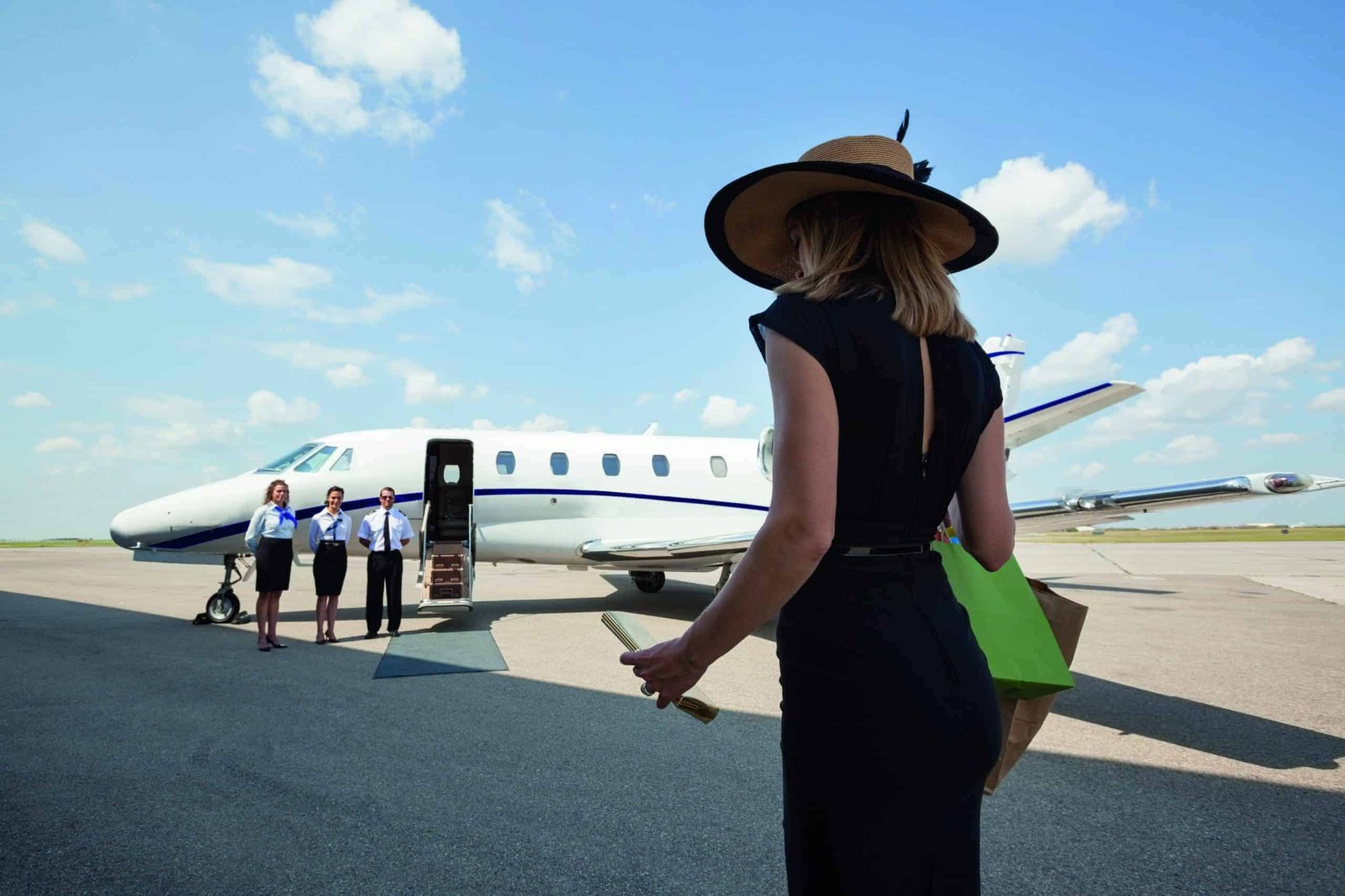 A woman in a black dress standing next to a private plane, discreetly under the radar.