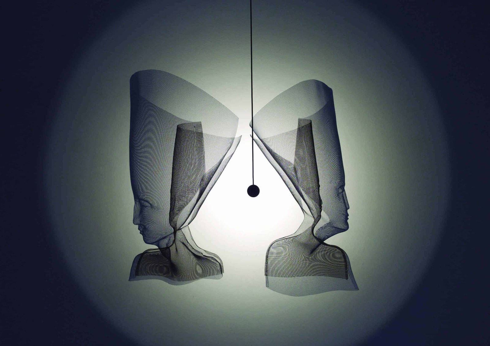 Two heads hanging from a lamp in a dimly lit room.