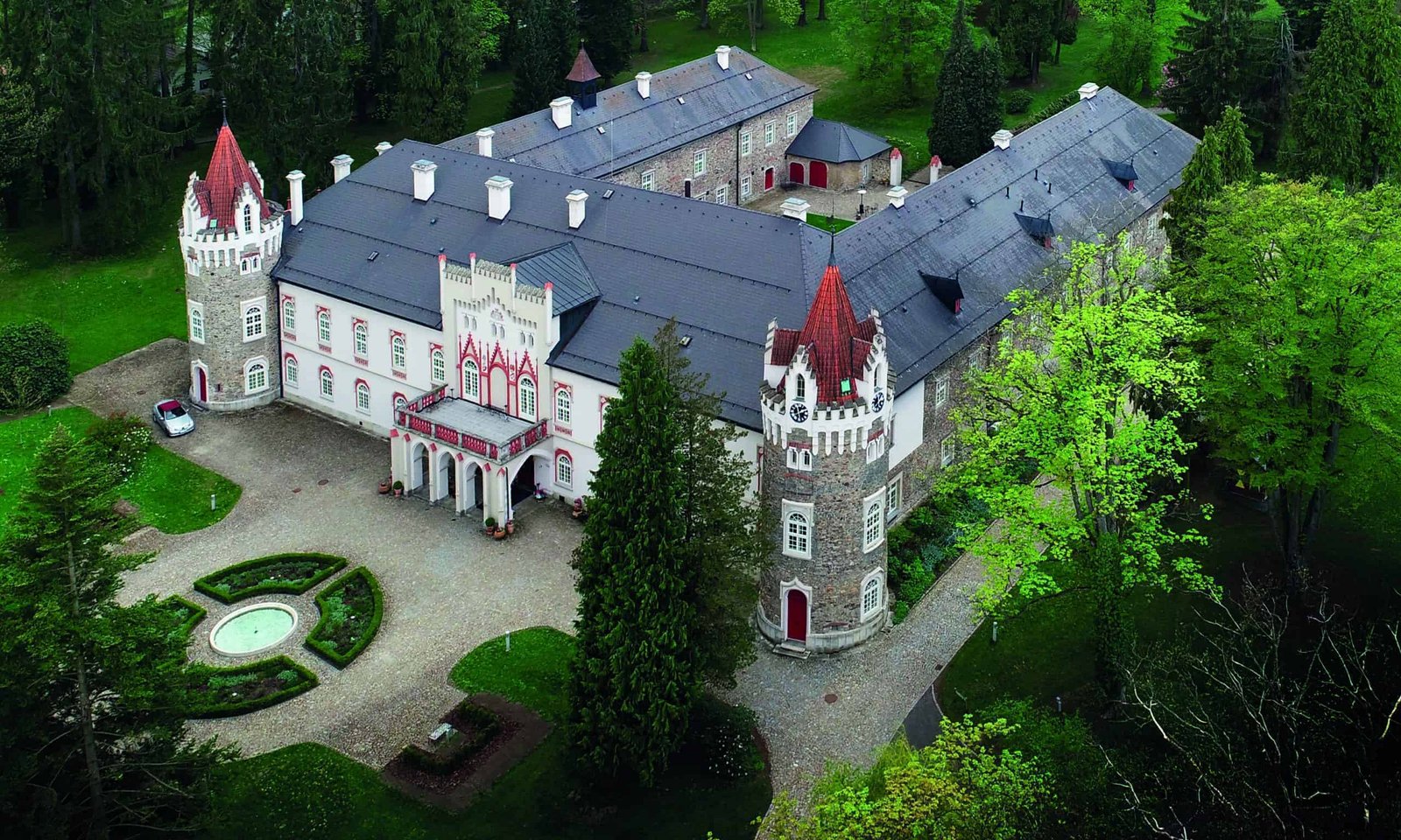 An aerial view of a luxury castle surrounded by trees.