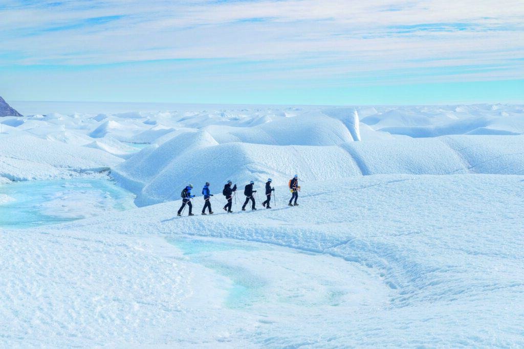 A group of people embarks on a lifetime trip, walking across a snow-covered area.
