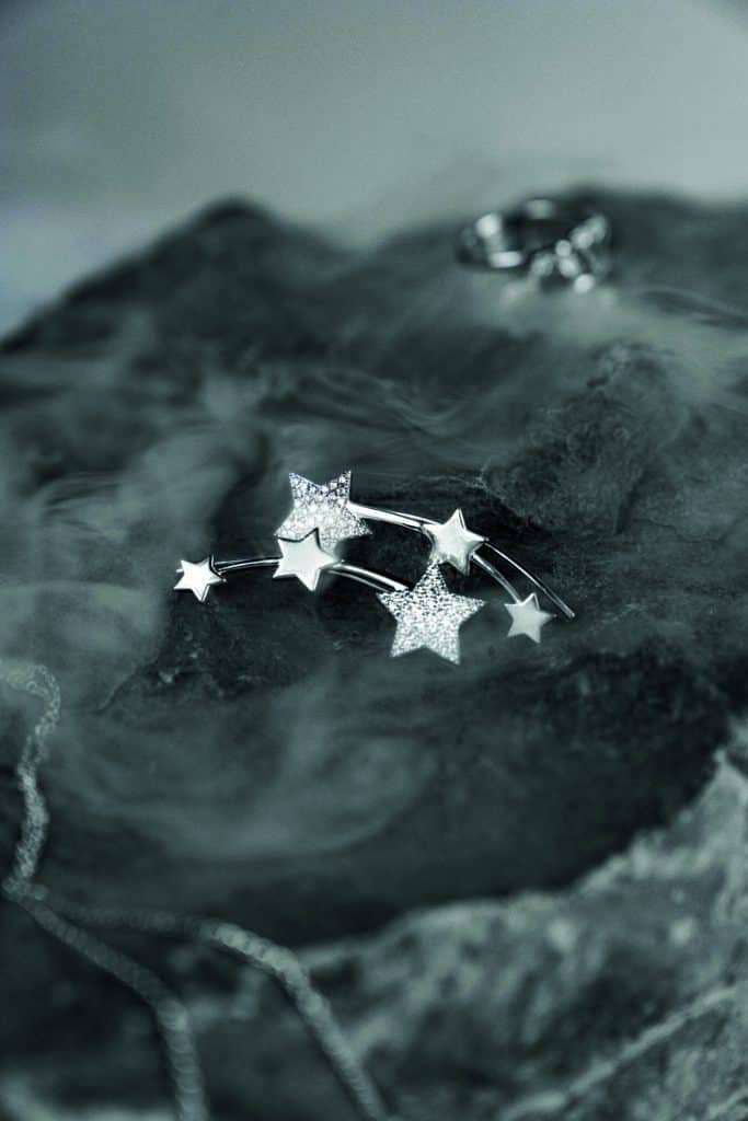 A silver star shaped brooch with diamonds on top of a rock.
