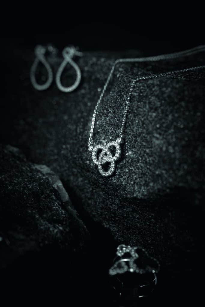 A black and white photo of a necklace and earrings with diamonds on a rock.