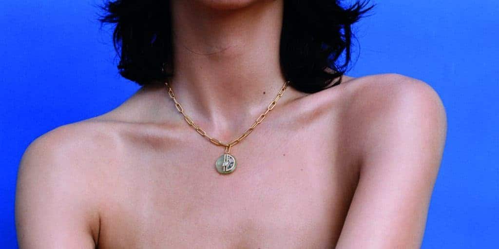 A woman is posing with a classic necklace on her chest, giving it a twist of elegance.