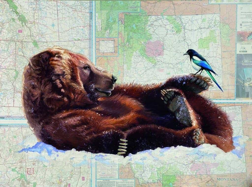 A wild brown bear laying on top of a map.
