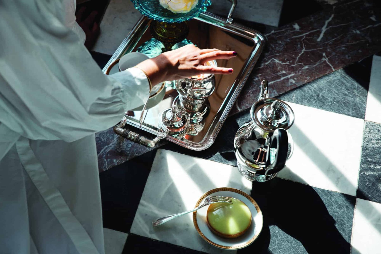 An artistically dressed woman gracefully holds a tray on a table.