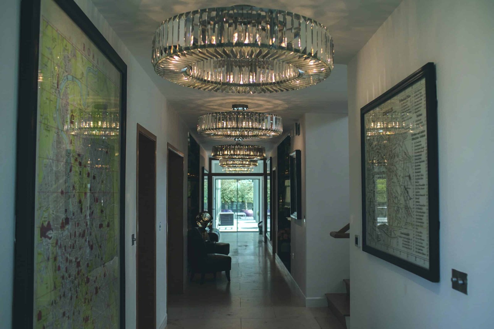 A hallway with a chandelier creating luminous effects and adorned with framed pictures.