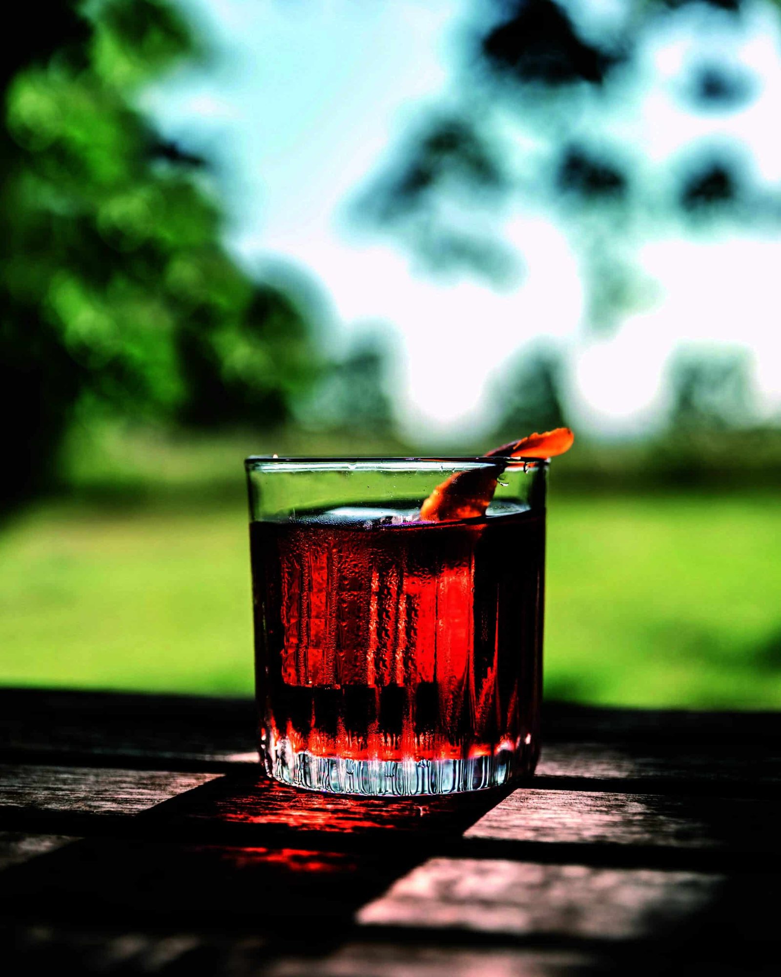 A glass of red liquid sitting on a wooden table, connecting nature.