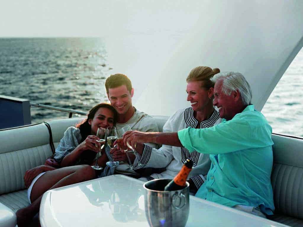 A group of people away on a sailing boat, toasting.