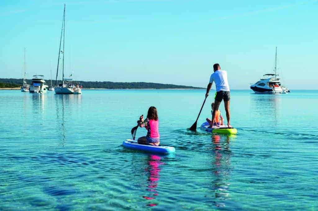 A man and a woman paddle boarding away in the water.