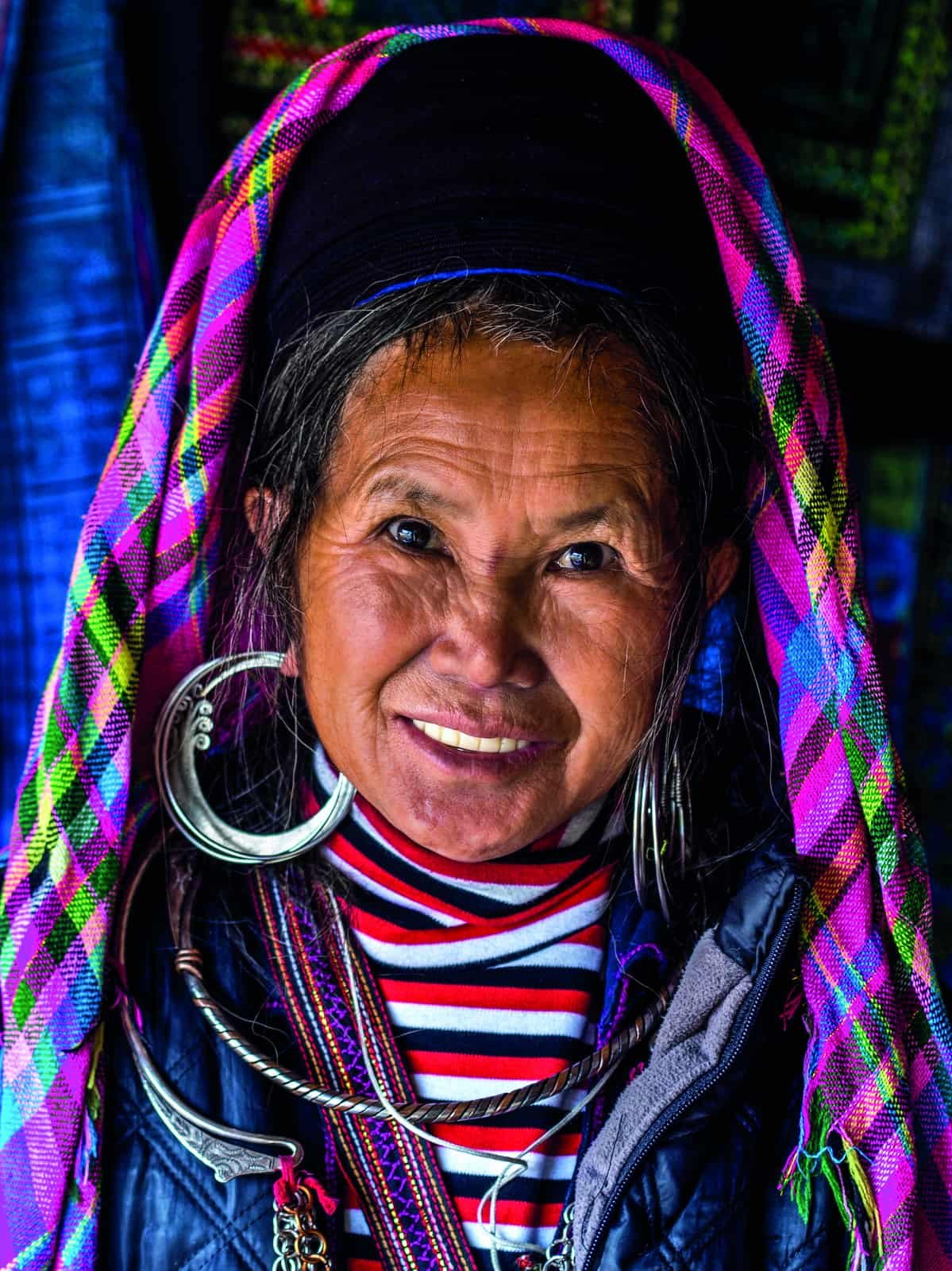 A woman with a vibrant soul, wearing a colorful scarf and hoop earrings, gracefully embodies the spirit of travel.