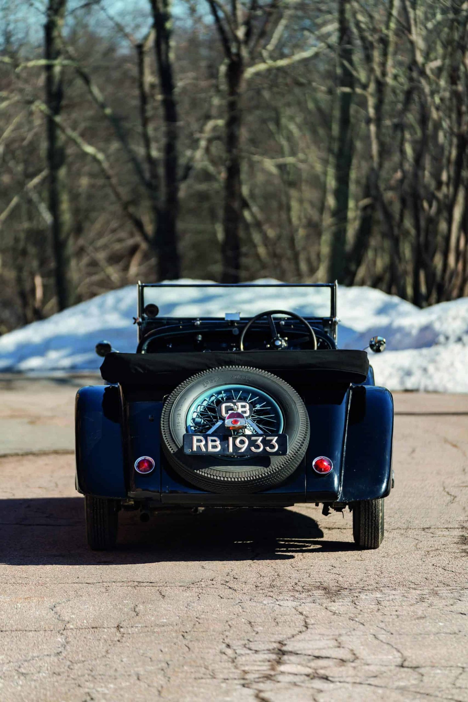 A vintage car is parked on a snowy road, offering the best of both worlds with its classic black exterior.