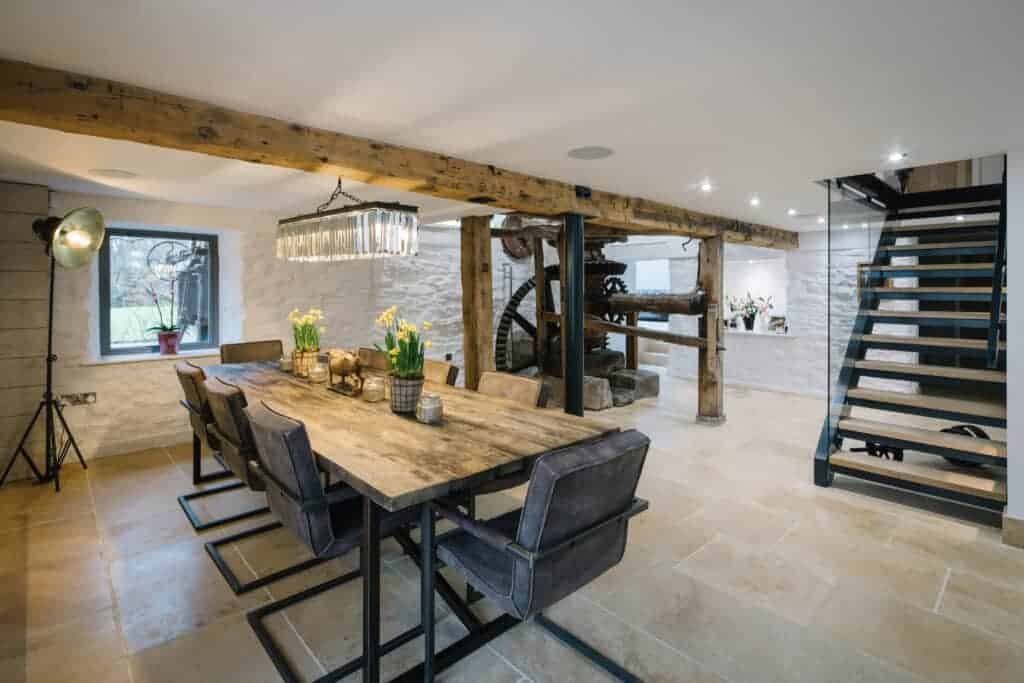 A nature-inspired dining room with a wooden staircase and rustic beams.