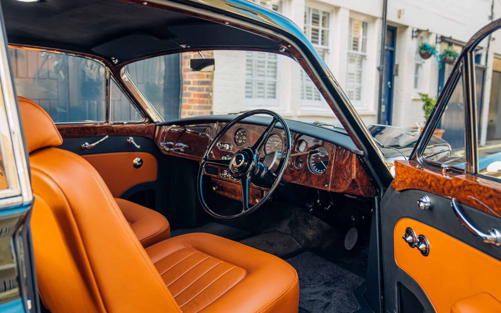 The interior of an old classic car with orange leather seats.